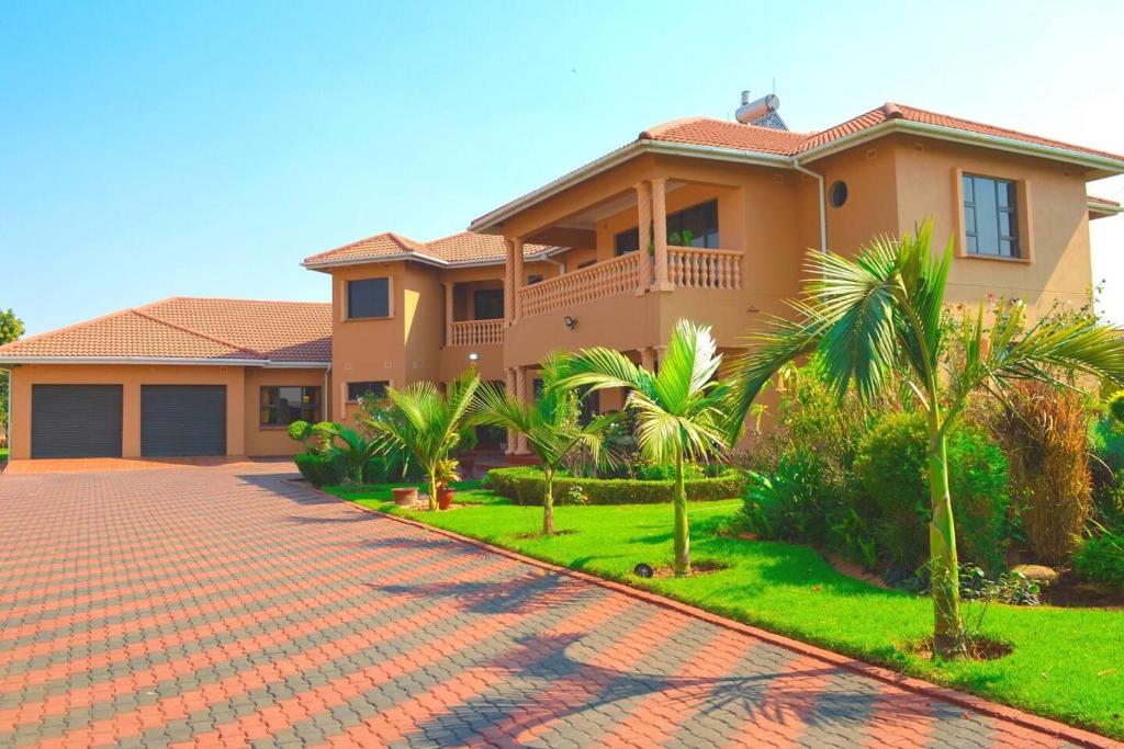Double-storey villa with tiled roof, balconies, palms and paved driveway