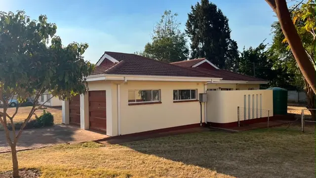 Single-storey home with garage, garden wall and mature trees